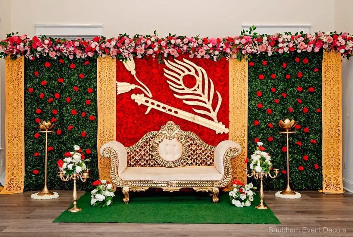 Reception stage with a red-and-green floral backdrop, gold panels and an ornate cream-and-gold sofa